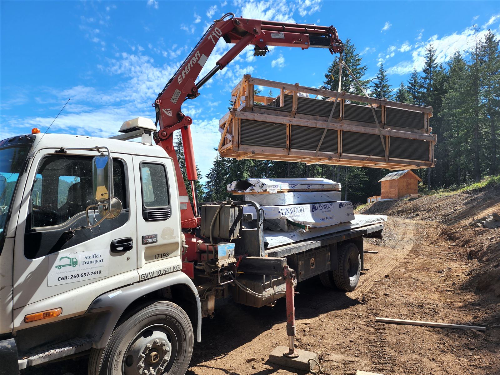 Crane lifting a crated load off the truck at a building site